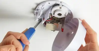 Certified technician wiring smoke detector during installation in Lancaster, PA